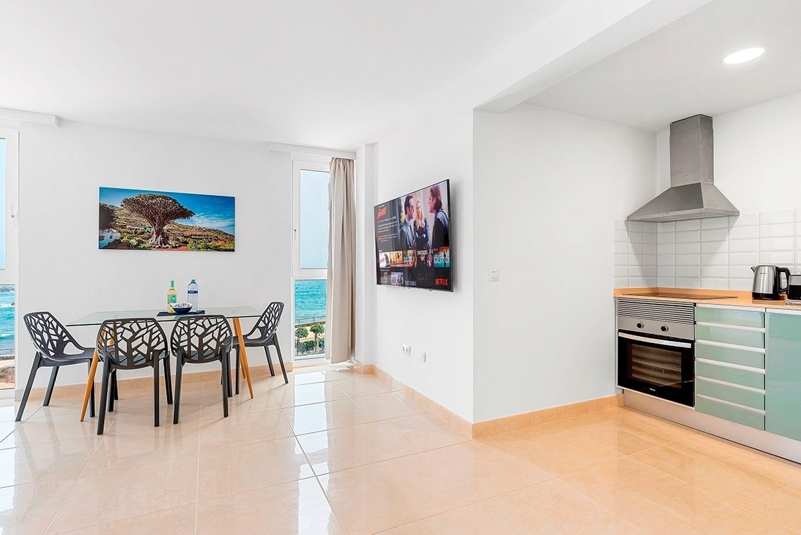 una cucina con un tavolo e sedie e un televisore che mostra netflix
