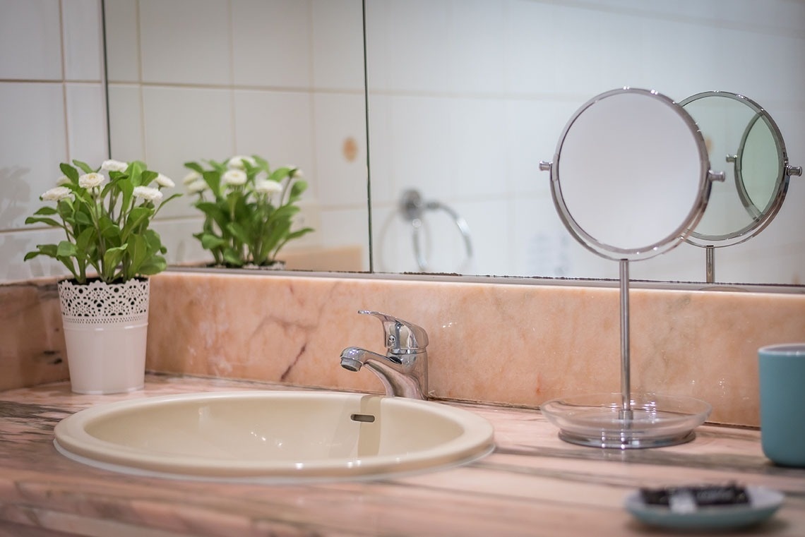 un lavandino in un bagno con due specchi e un vaso di fiori