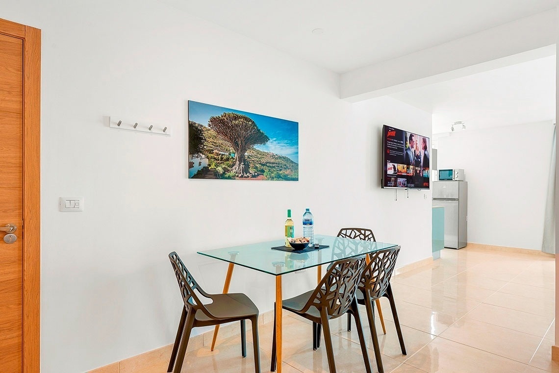 una stanza con un tavolo e sedie e un televisore che mostra netflix