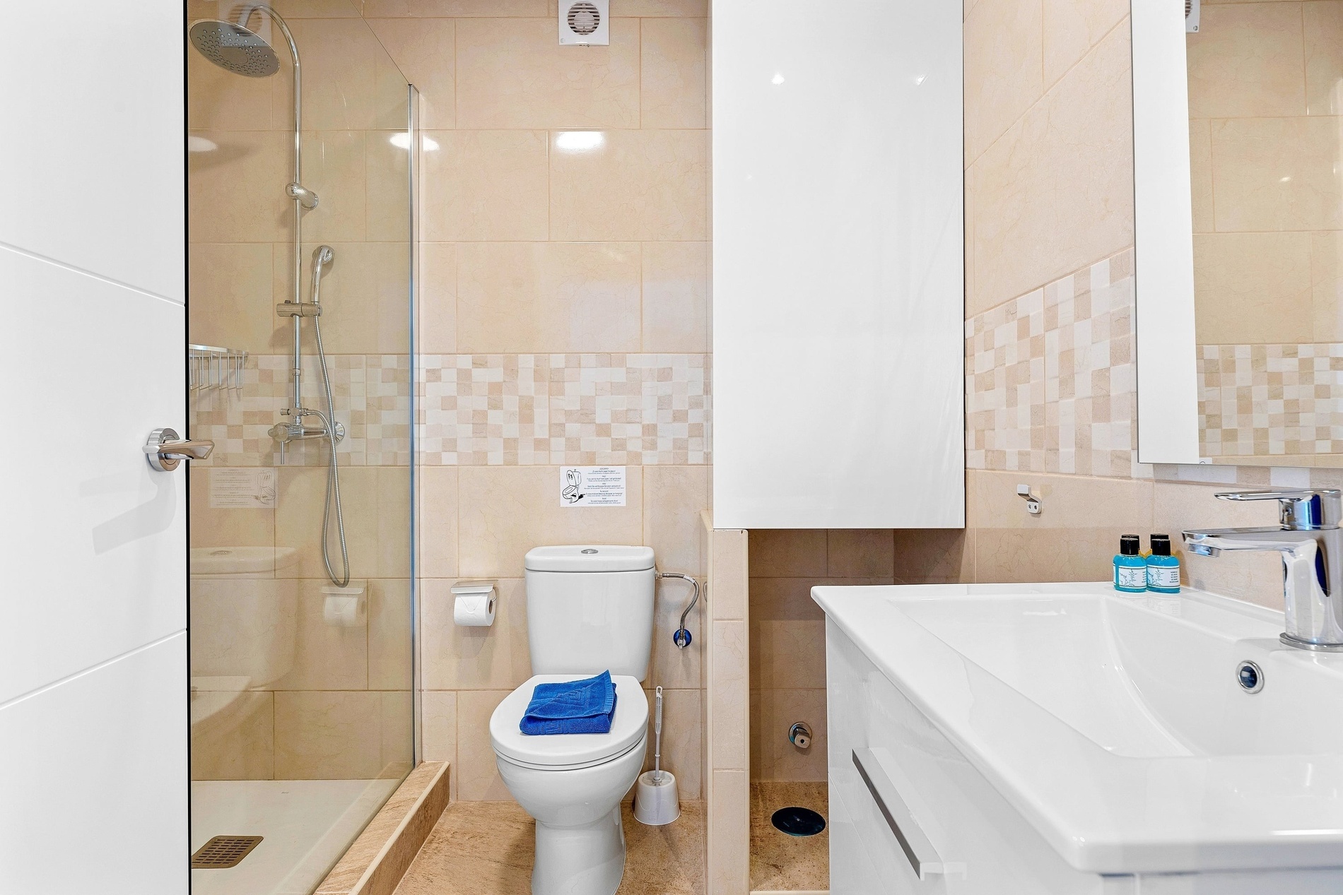 Une salle de bain moderne et propre avec douche, toilettes et lavabo, décorée de carrelage beige.