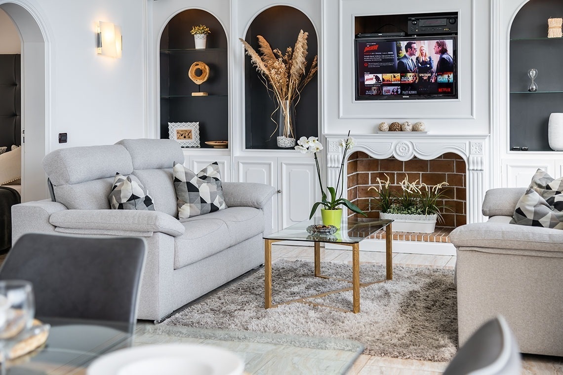 un soggiorno con un divano e un camino e un televisore che mostra netflix