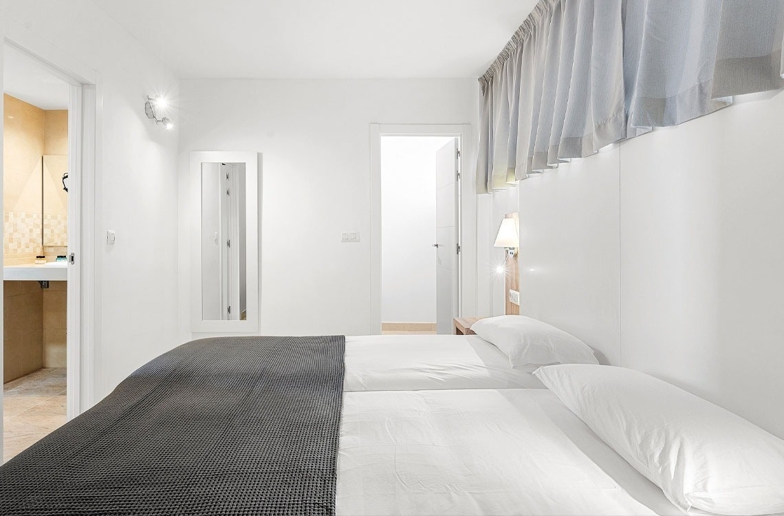 una camera da letto con due letti e una porta che conduce al bagno