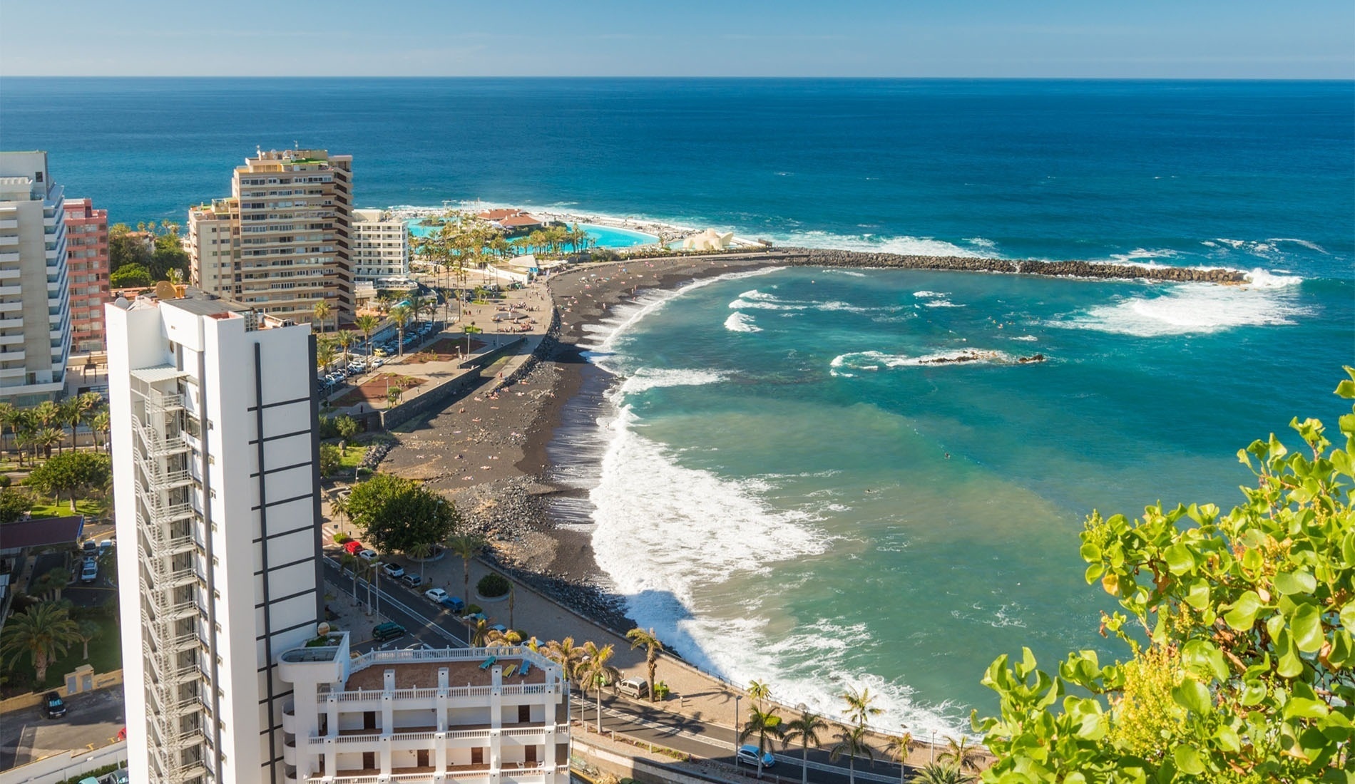 una piscina rodeada de sillas y plantas con edificios en el fondo