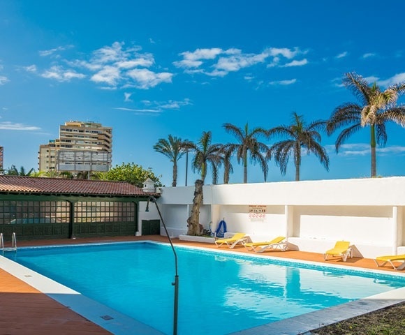 una cama con dosel y una piscina en el fondo
