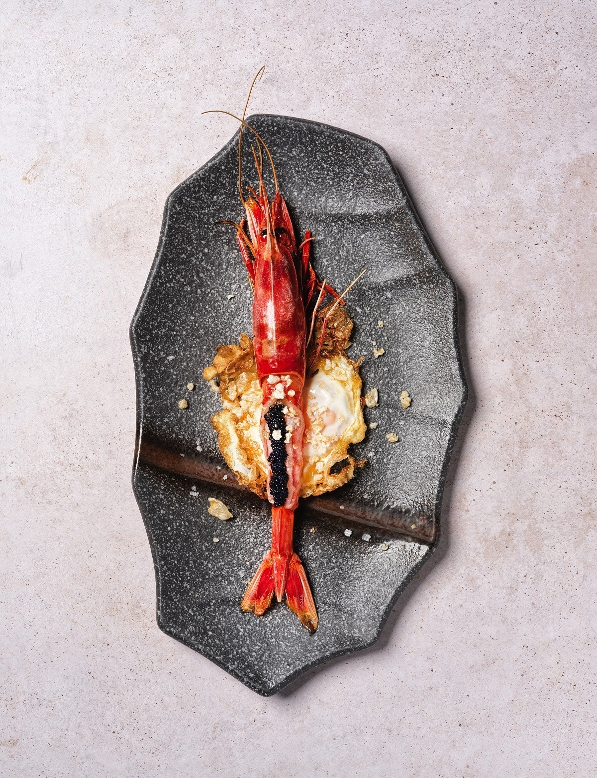 a black plate with a red shrimp on it