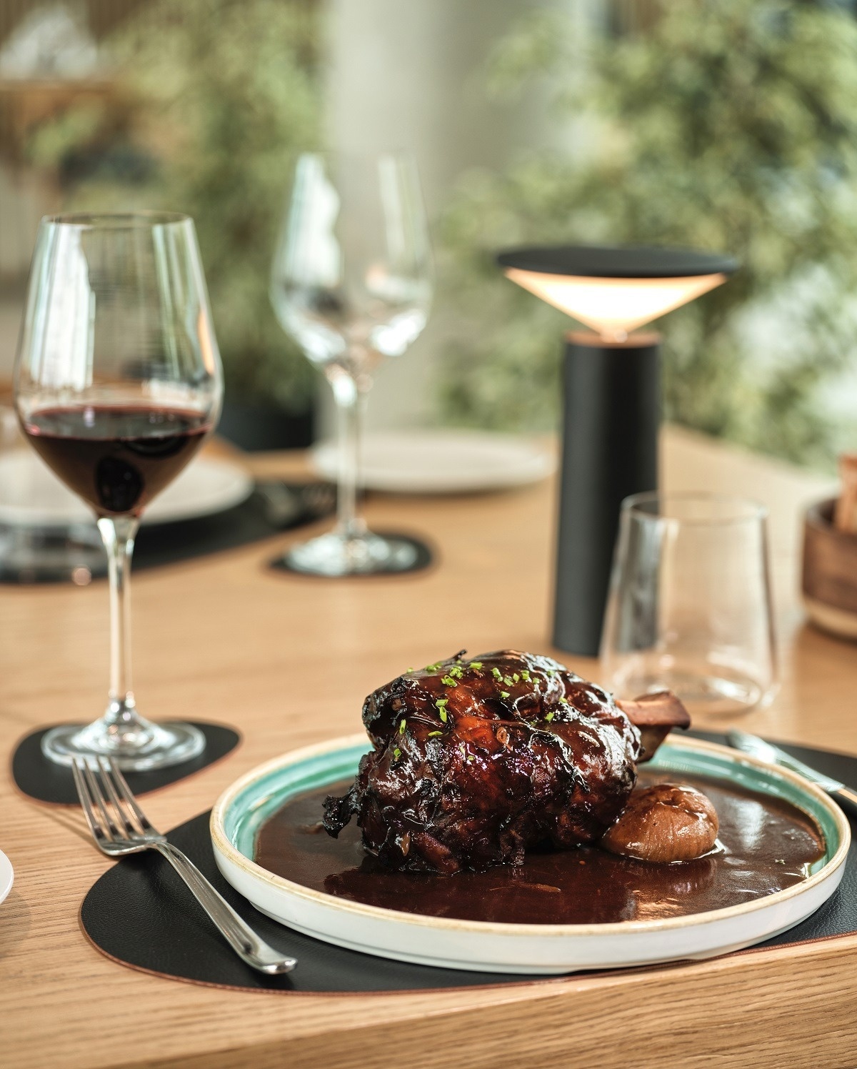 a plate of food sits on a table next to a glass of wine