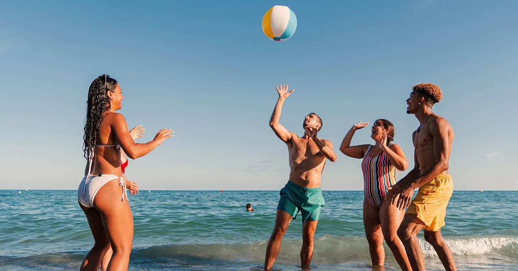 un grupo de jóvenes está jugando con una pelota de playa en la playa