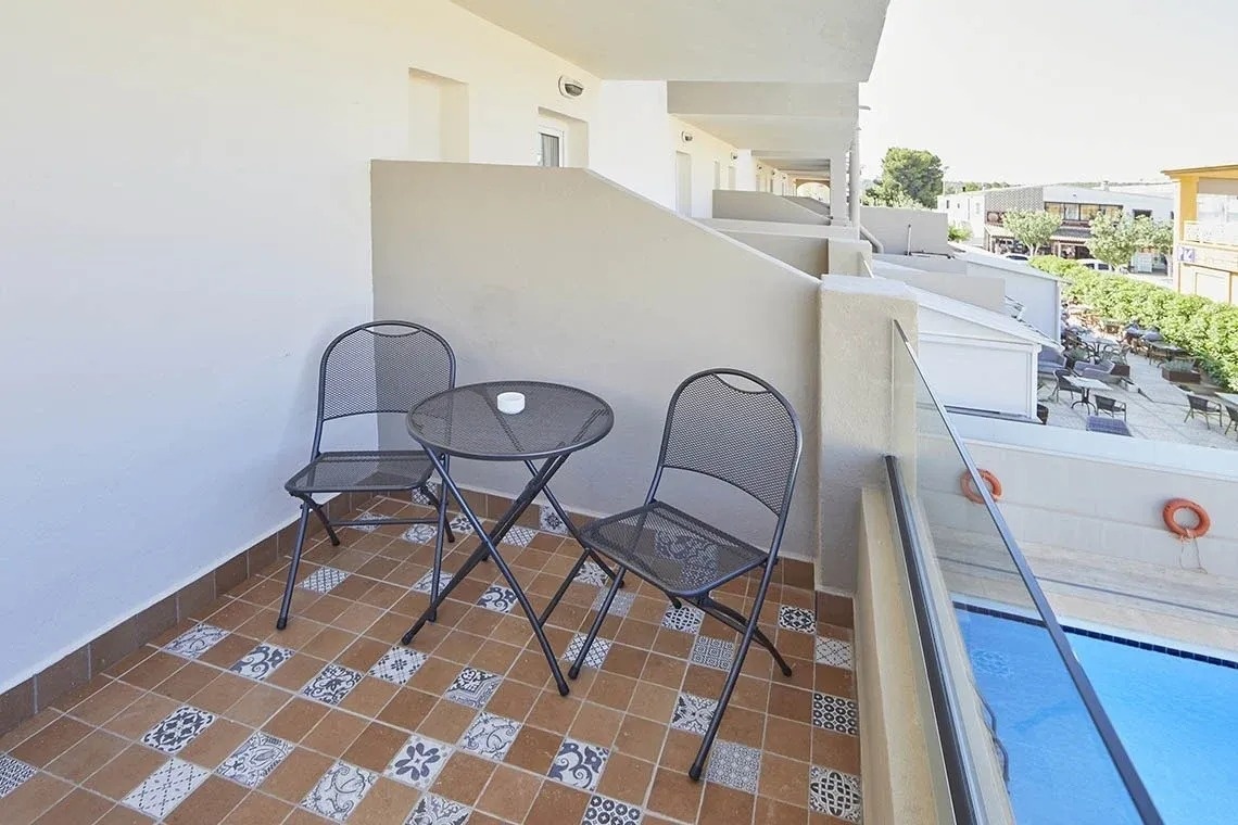 un balcón con una mesa y dos sillas junto a una piscina