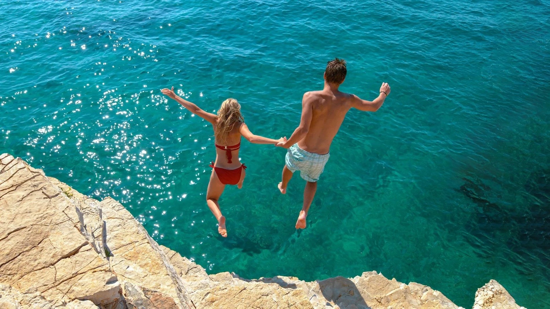 a man and a woman are jumping into the ocean