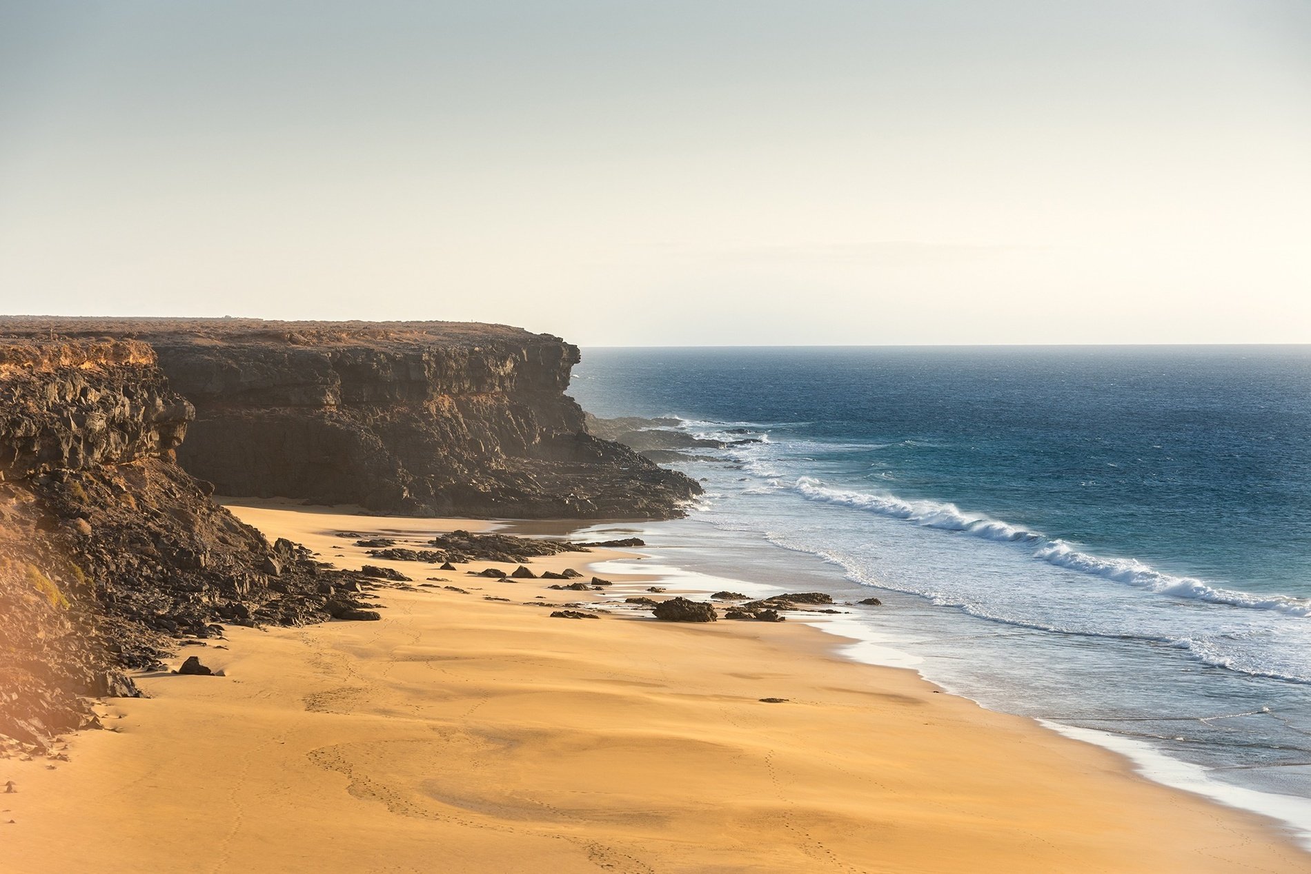 una playa de arena con un acantilado en el fondo