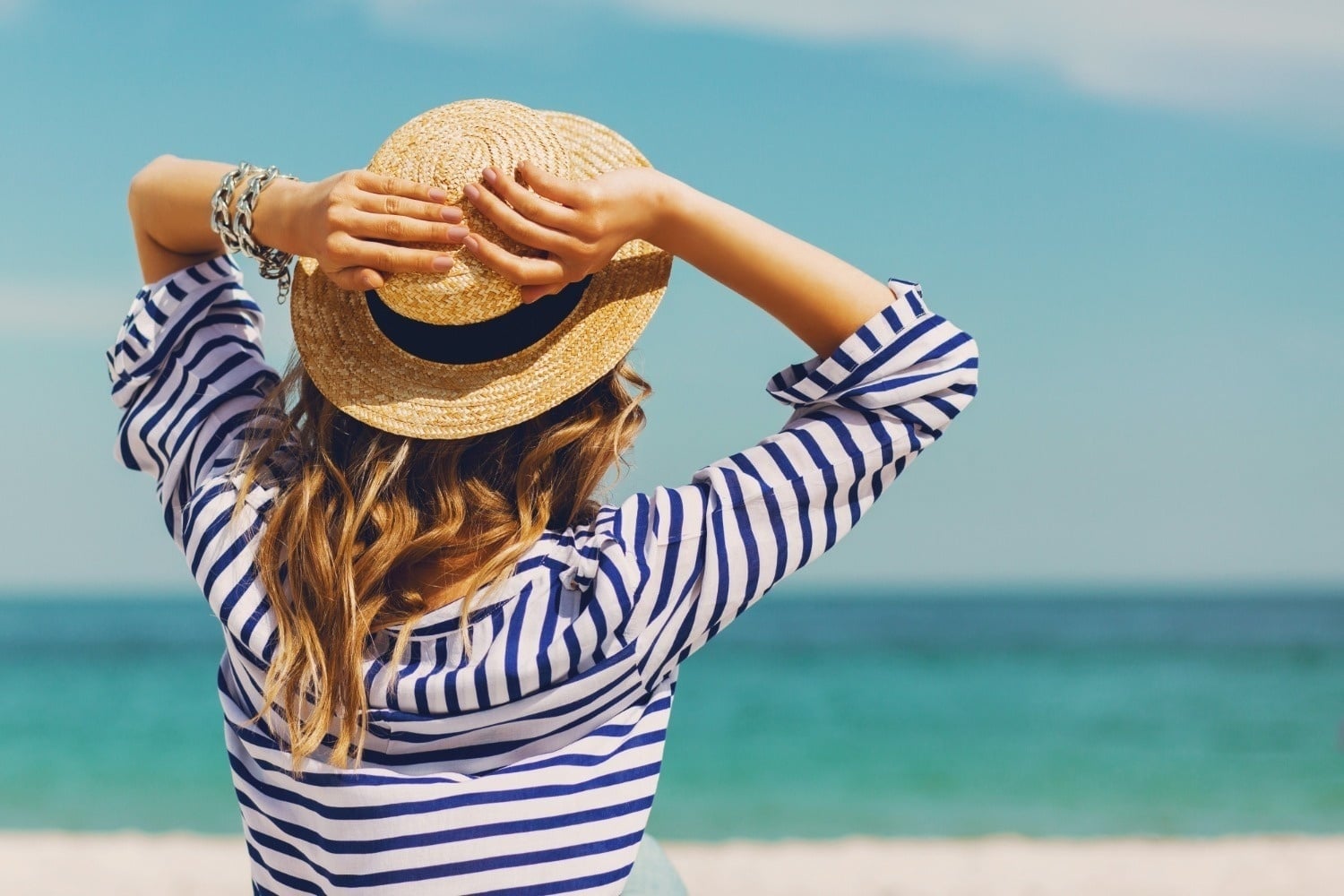 Mujer relajada en la playa con sombrero y mar. O7 HOTELS: Corporativa.