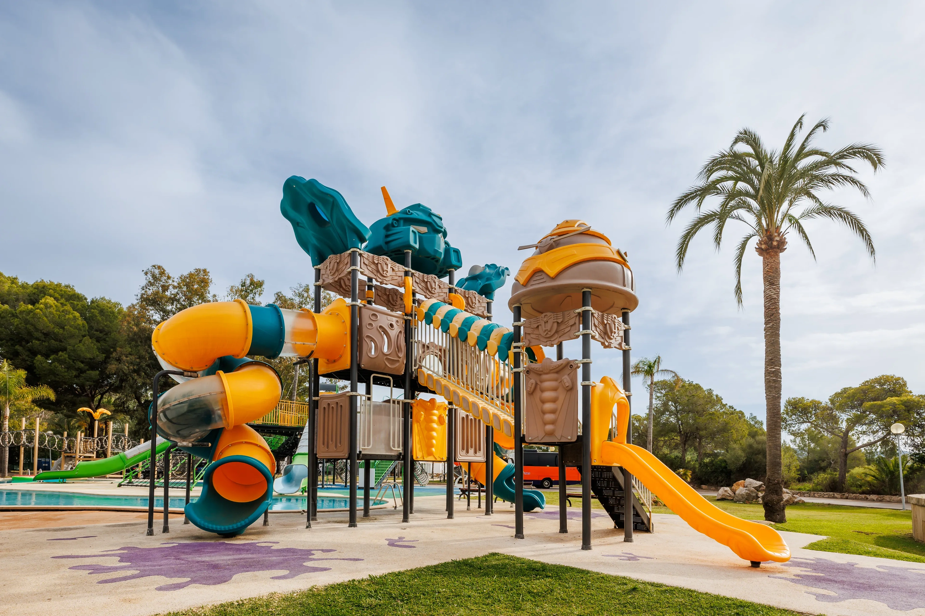 O7 HOTELS: Corporativa - Parque infantil colorido junto a piscina y palmeras.