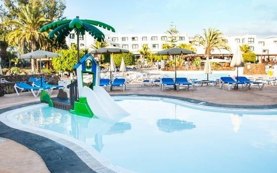 una piccola piscina con scivolo e palme in un resort .