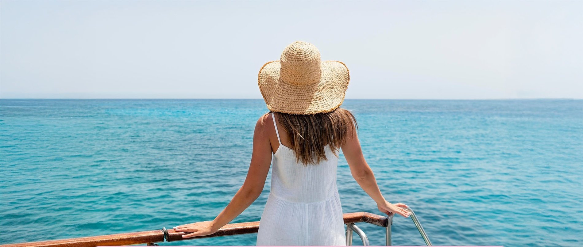 a woman wearing a straw hat looks out over the ocean