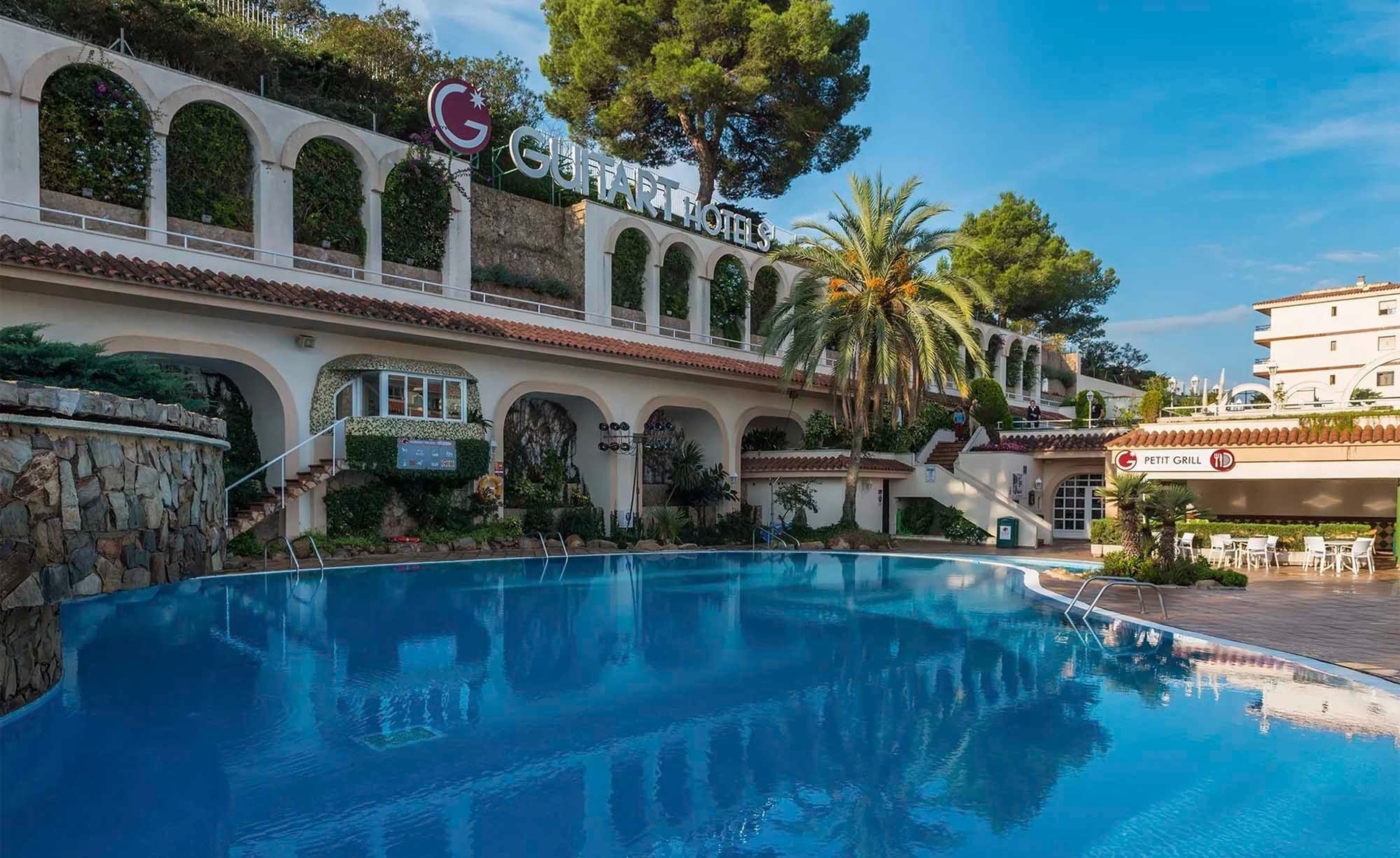 una donna in piedi su un balcone di una casa rosa con tendaggi verdi