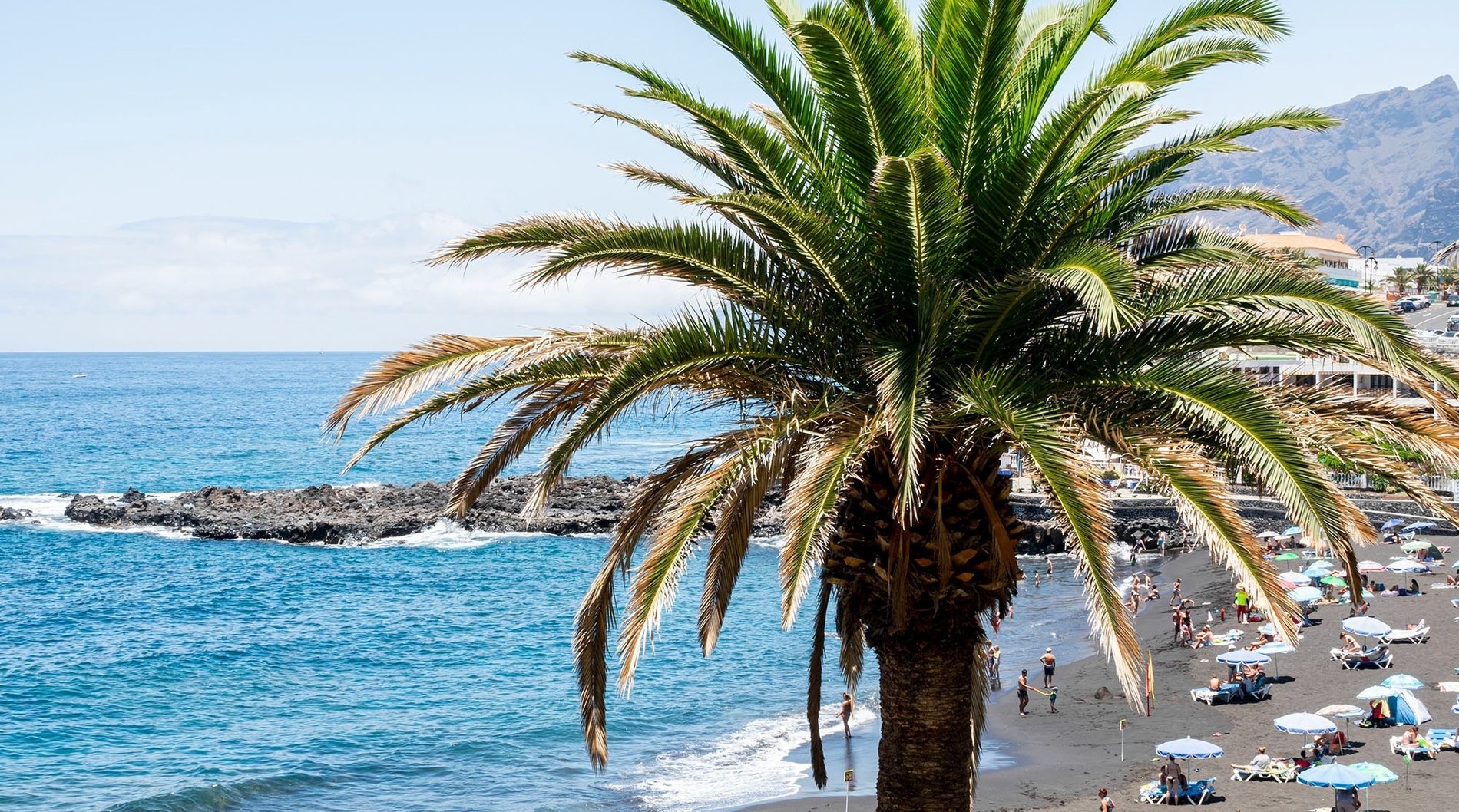 a sandy beach with a rocky cliff in the background