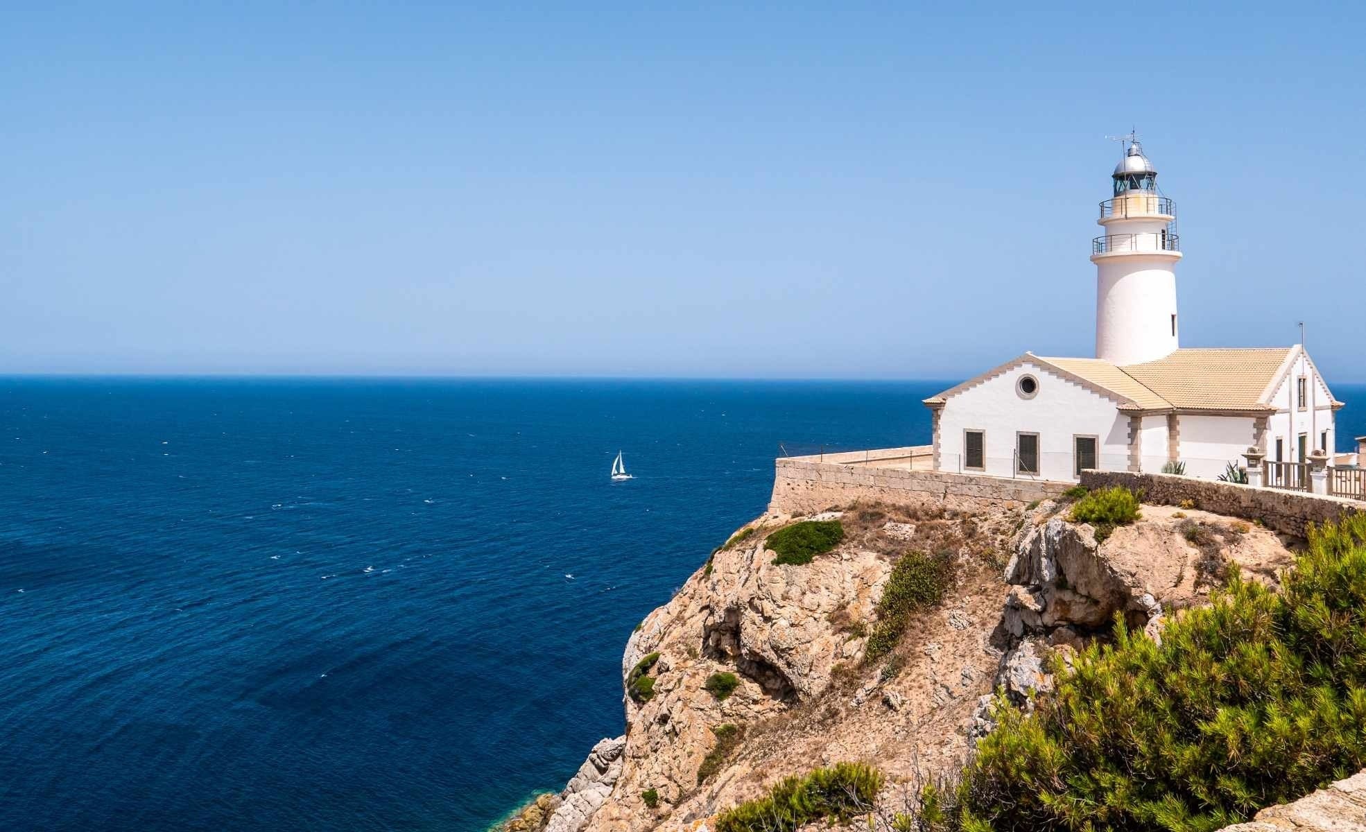 un faro está en la cima de una colina con vistas al océano