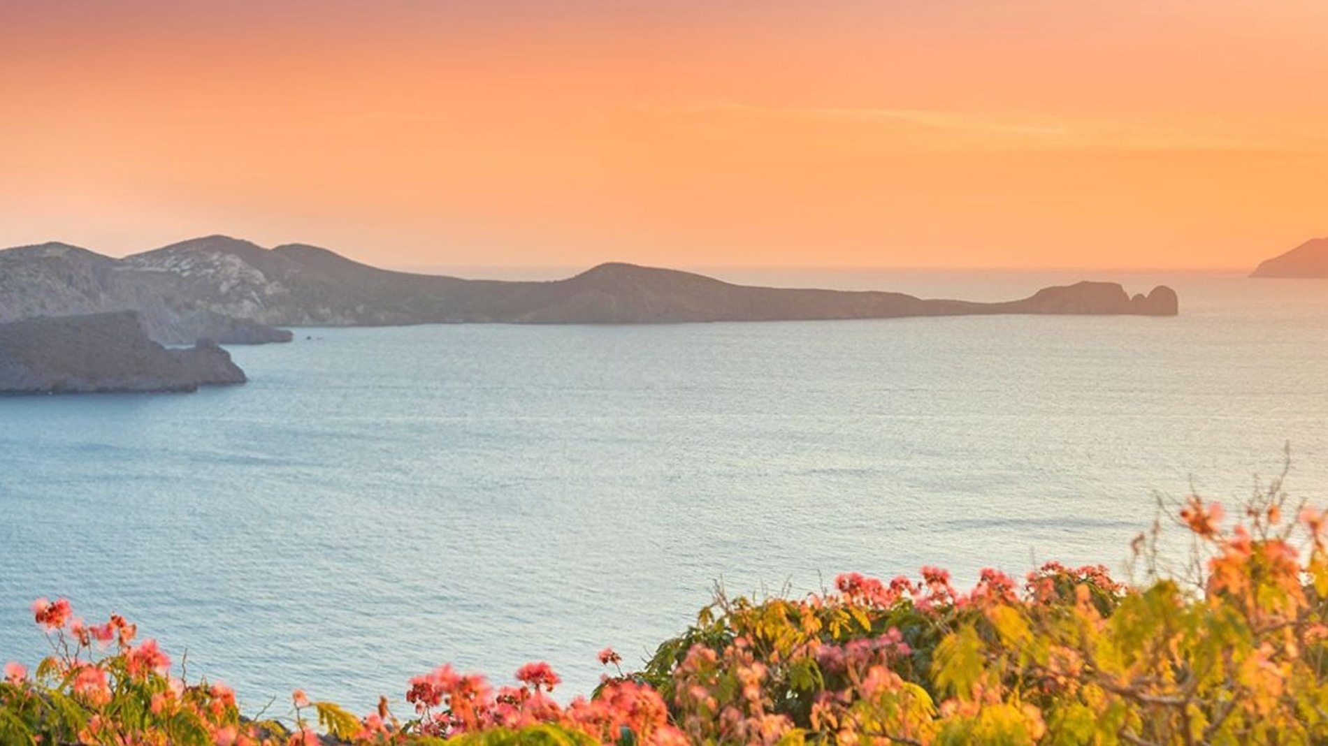 a sunset over a body of water with mountains in the background