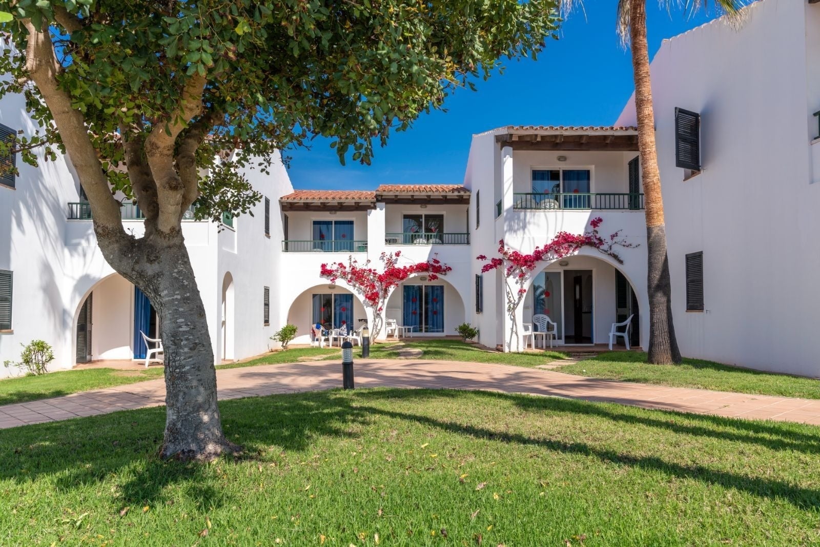 Weiße Apartments mit Bögen und Bougainvillea. Offizielle Web Vistapicas Apartments | O7 Vista Picas | Menorca.