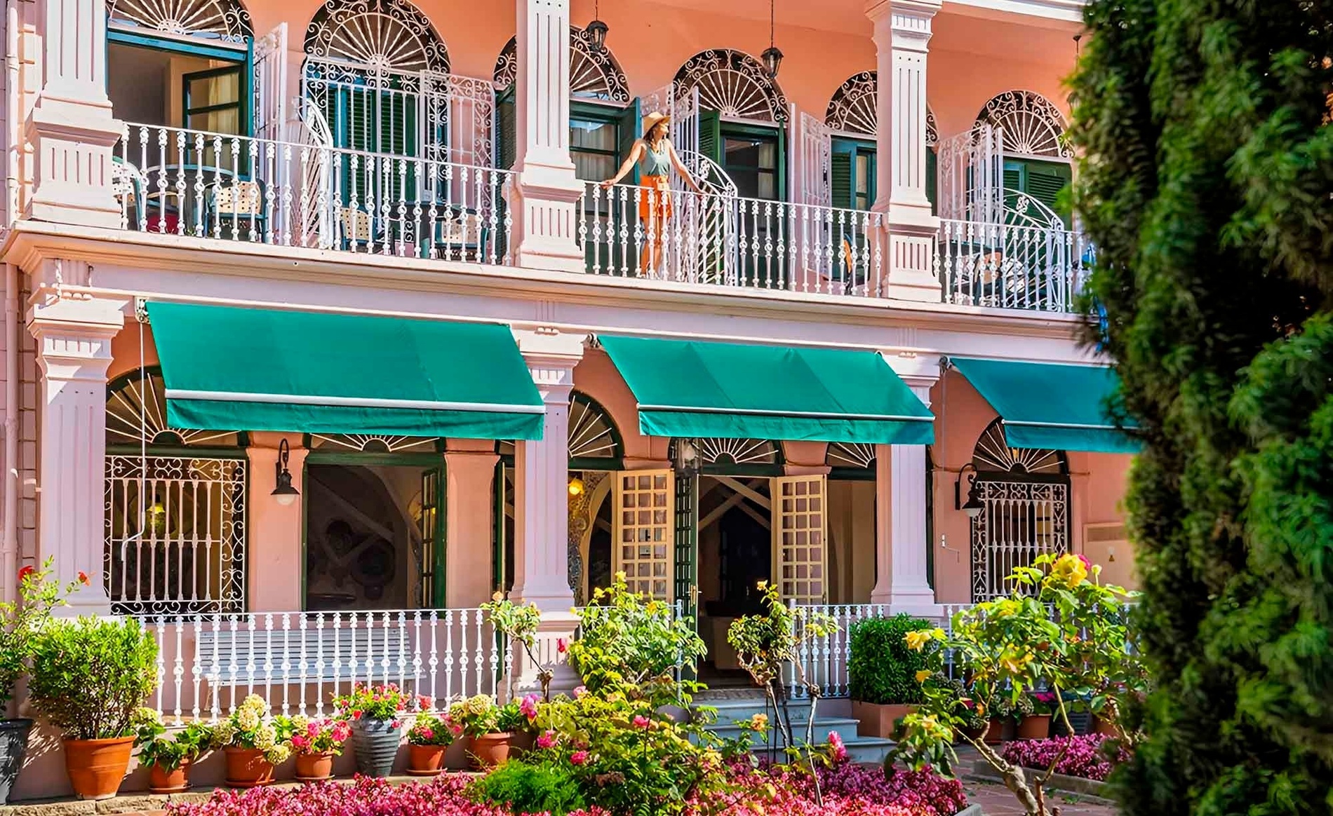 eine Frau steht auf einem Balkon mit grünen Vorhängen