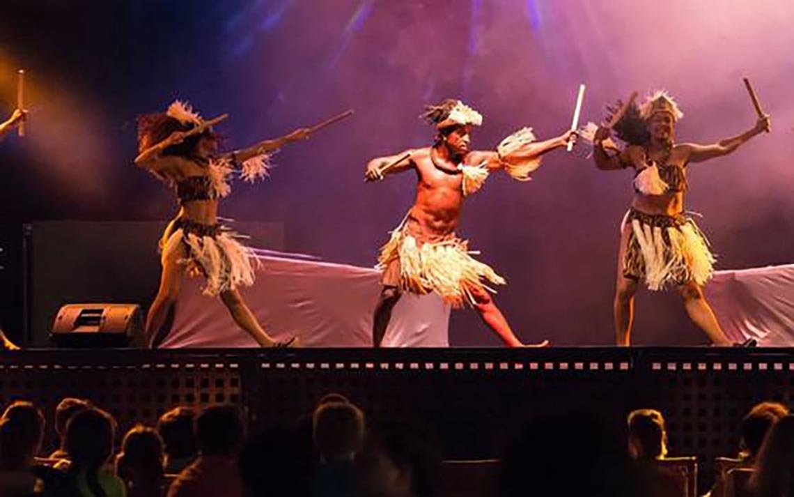 a group of people are dancing on a stage in front of a crowd .