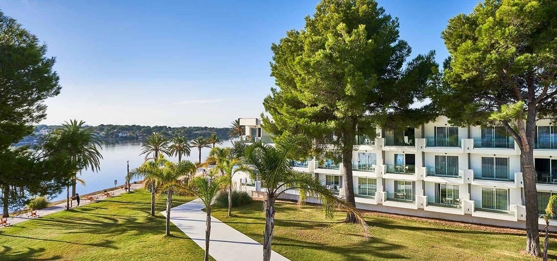 a large white building with lots of windows sits next to a body of water