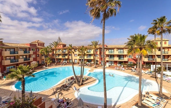 ein Hotel mit einem großen Pool und Palmen davor
