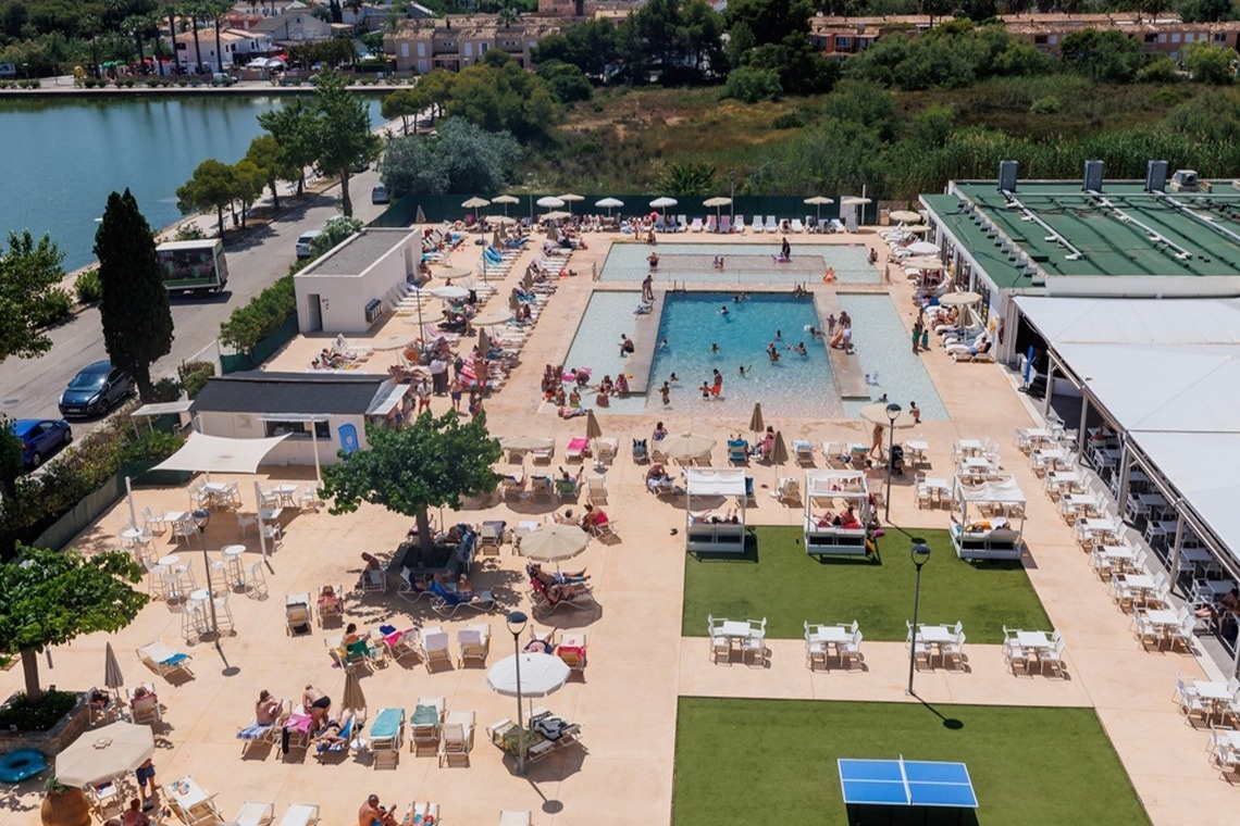 un gruppo di persone nuota in una grande piscina circondata da sedie e tavoli