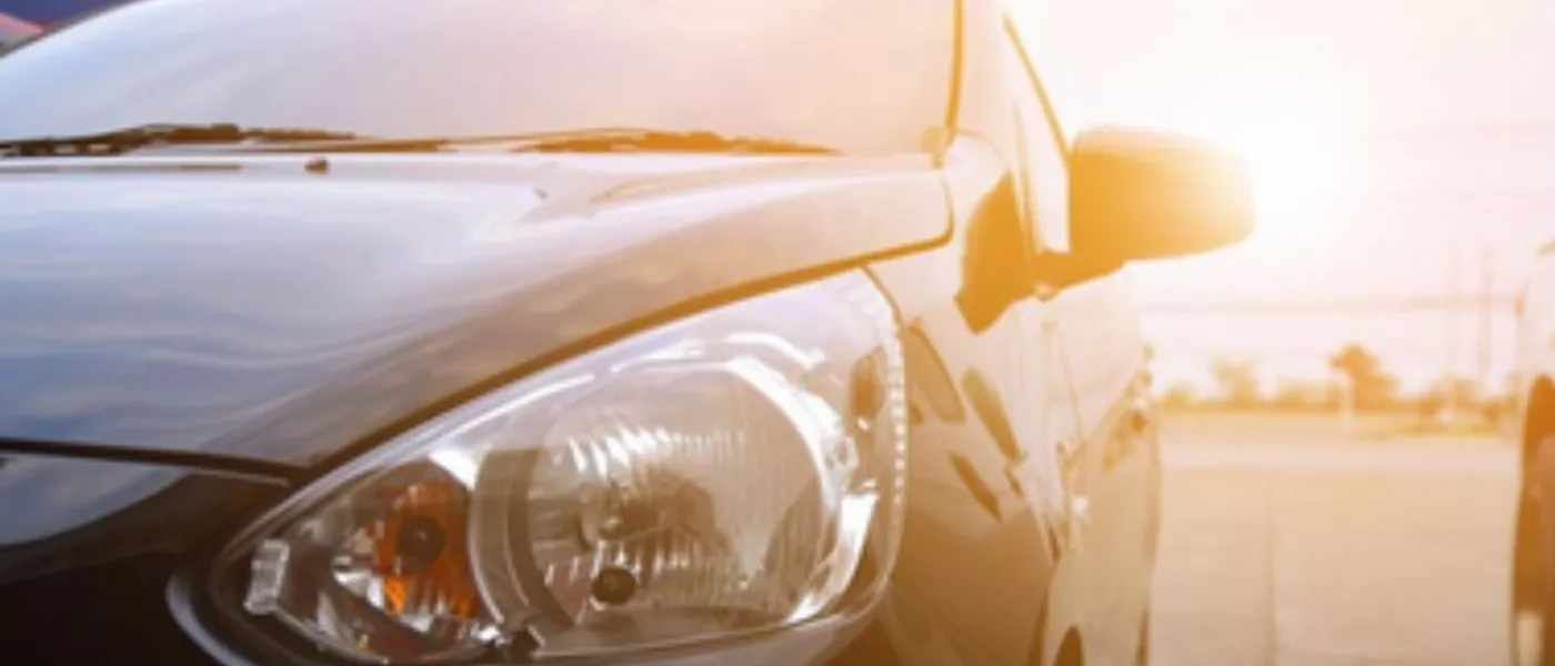 un primer plano del faro de un coche en un estacionamiento al atardecer .