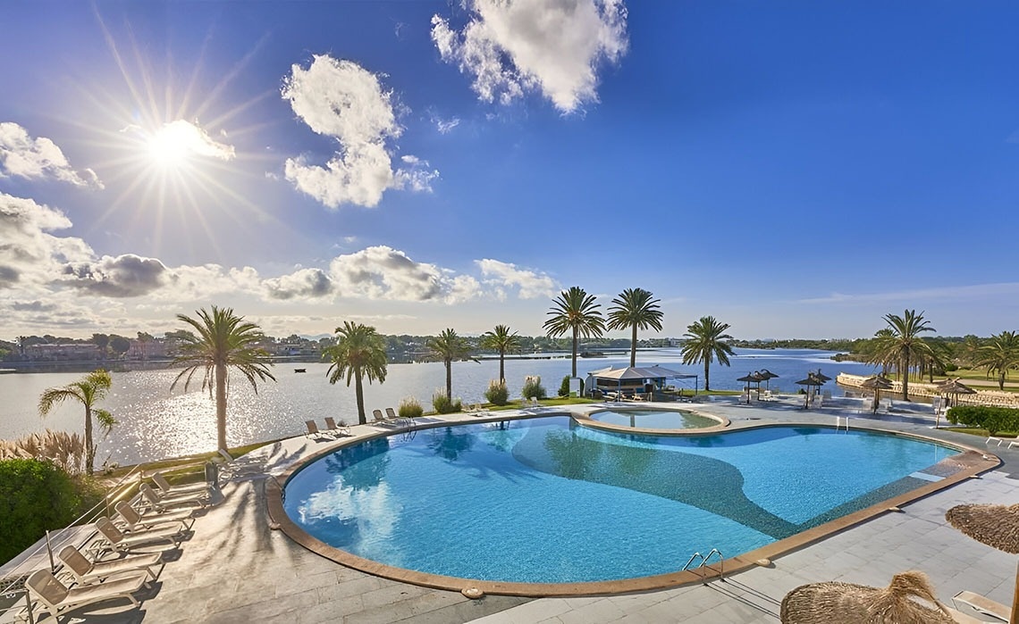 a large swimming pool surrounded by white buildings and palm trees