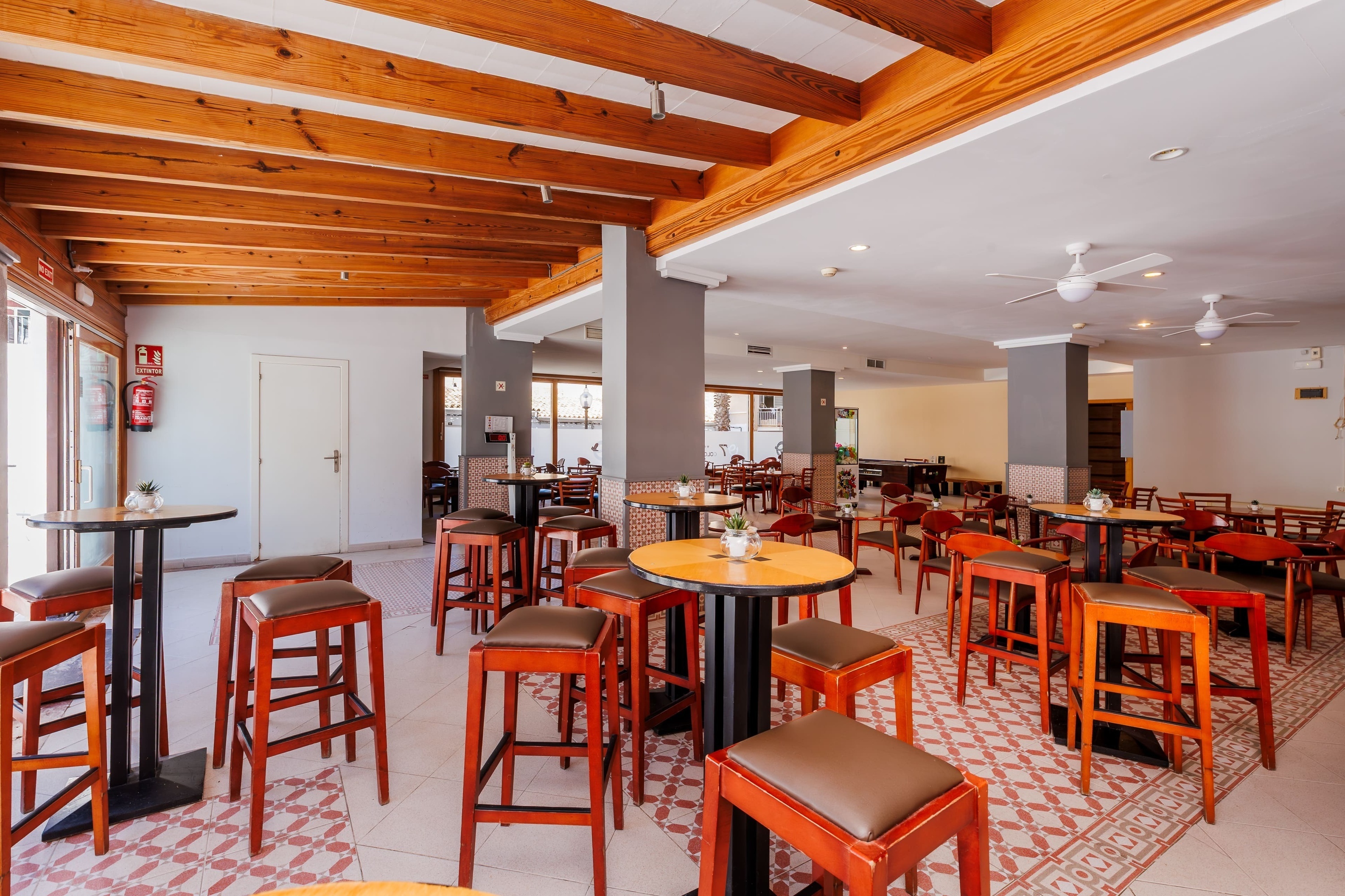 un restaurante con muchas mesas y sillas y un extintor de incendios en la pared