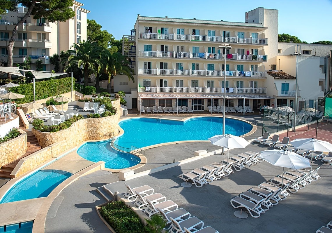 a large swimming pool surrounded by white buildings and palm trees
