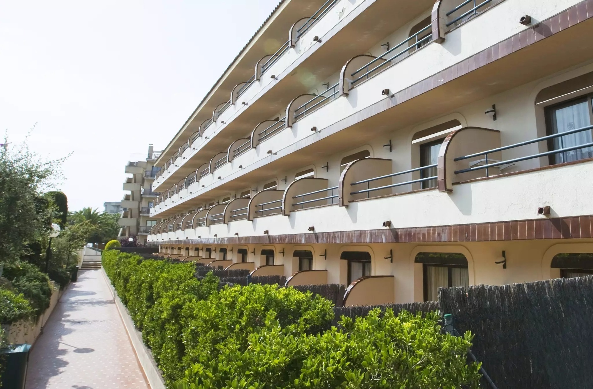 una mujer se para en un balcón de una casa rosa con toldos verdes