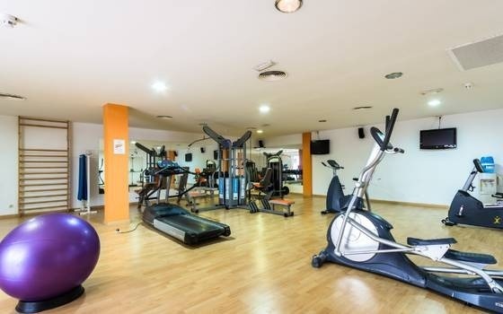 una palestra piena di macchine da ginnastica e una palla viola .