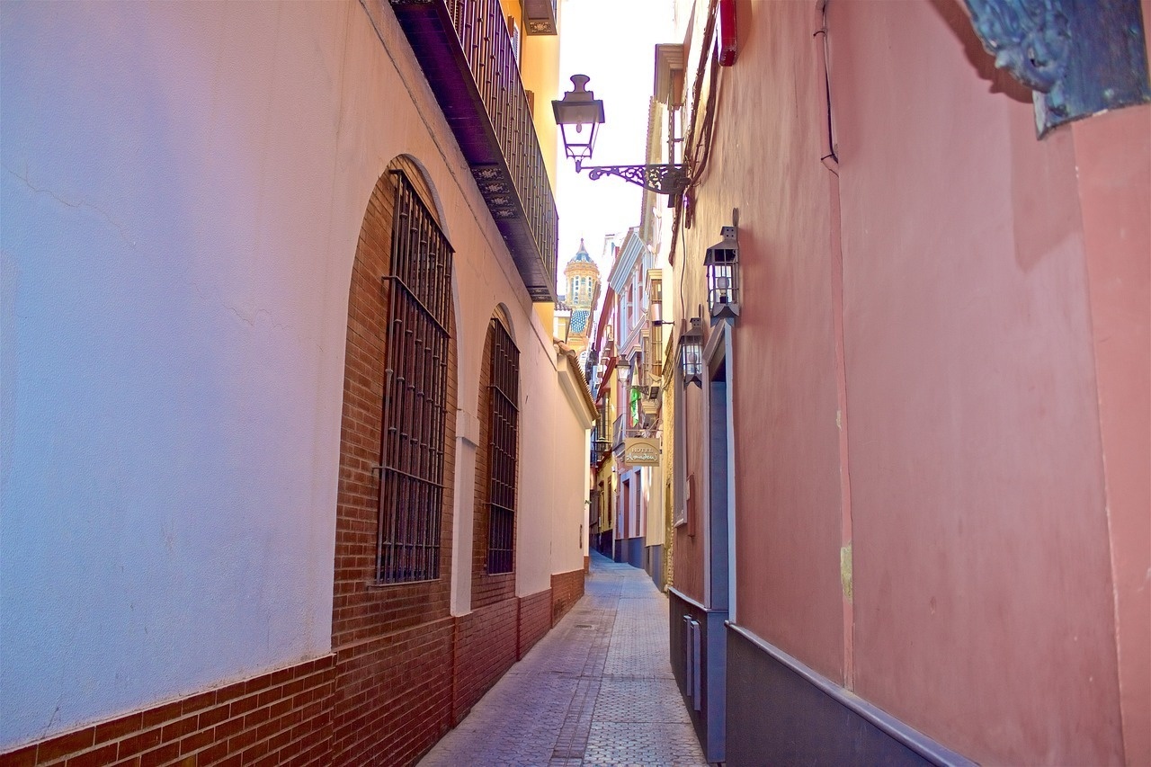 a narrow alleyway with a clock tower in the background