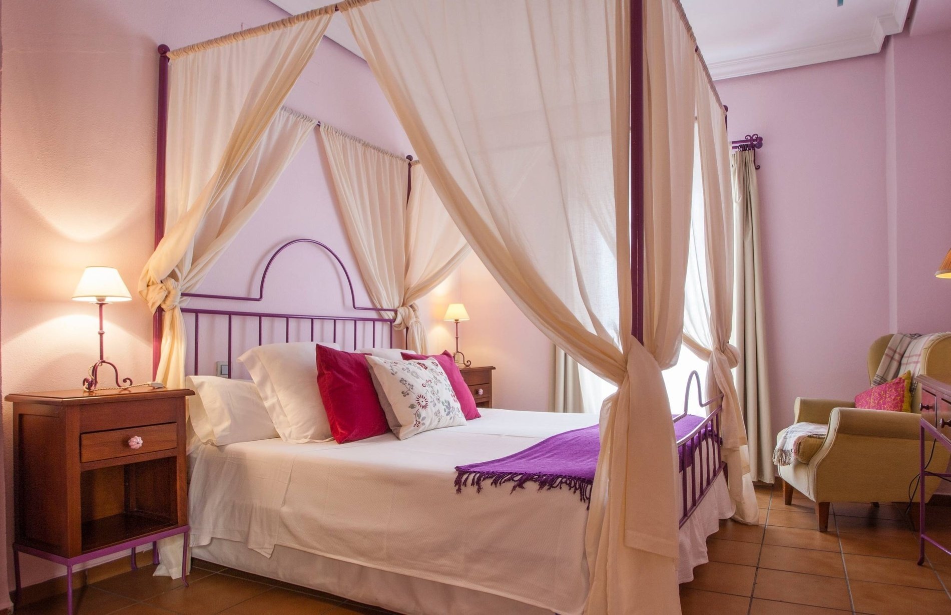 a bedroom with a canopy bed and pink walls