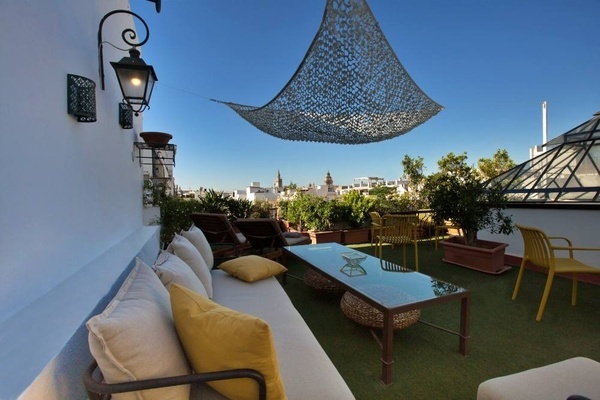 a patio with a couch and a table with a hammock hanging from the ceiling