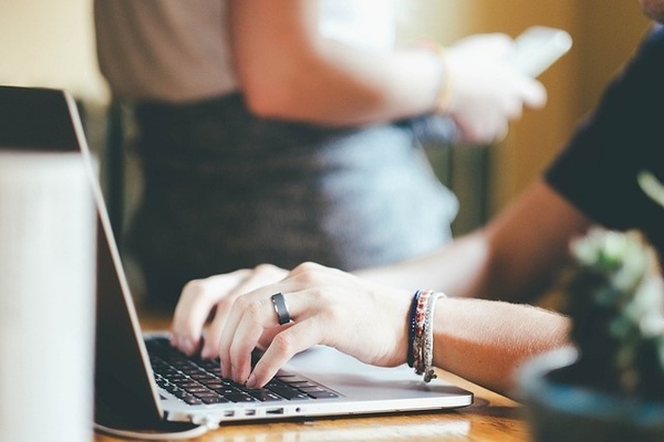 una persona con un anillo en la mano está escribiendo en una computadora portátil