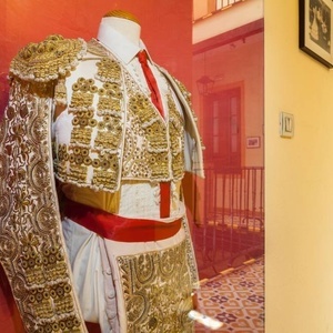 a mannequin wearing a bullfighter 's outfit is hanging on a red wall