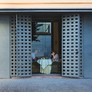 a man and a woman sit at a table outside of a building