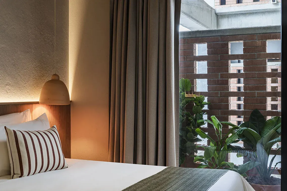 Habitación moderna en Obra Hotels Medellín con luz natural y plantas.