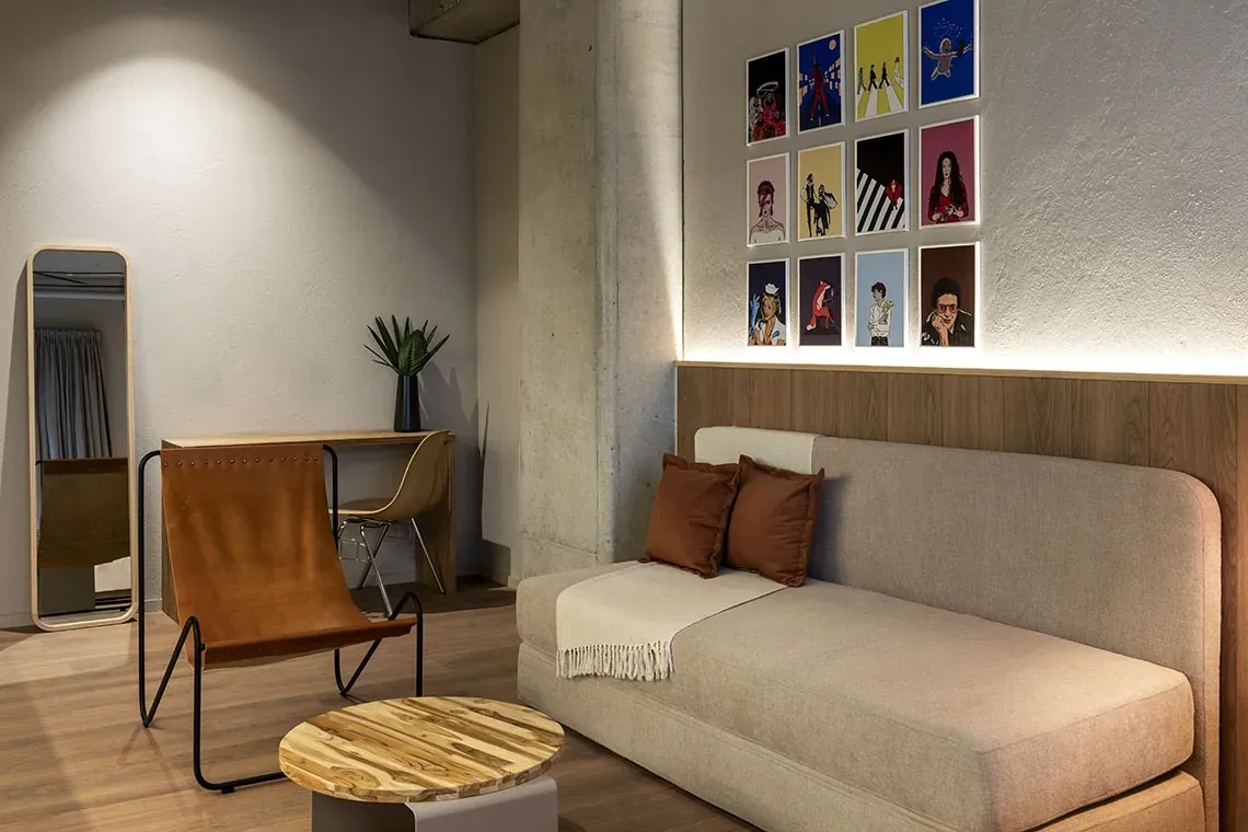 Acogedora sala de estar en Obra Hotels Medellín, con sofá, sillón y arte vibrante.