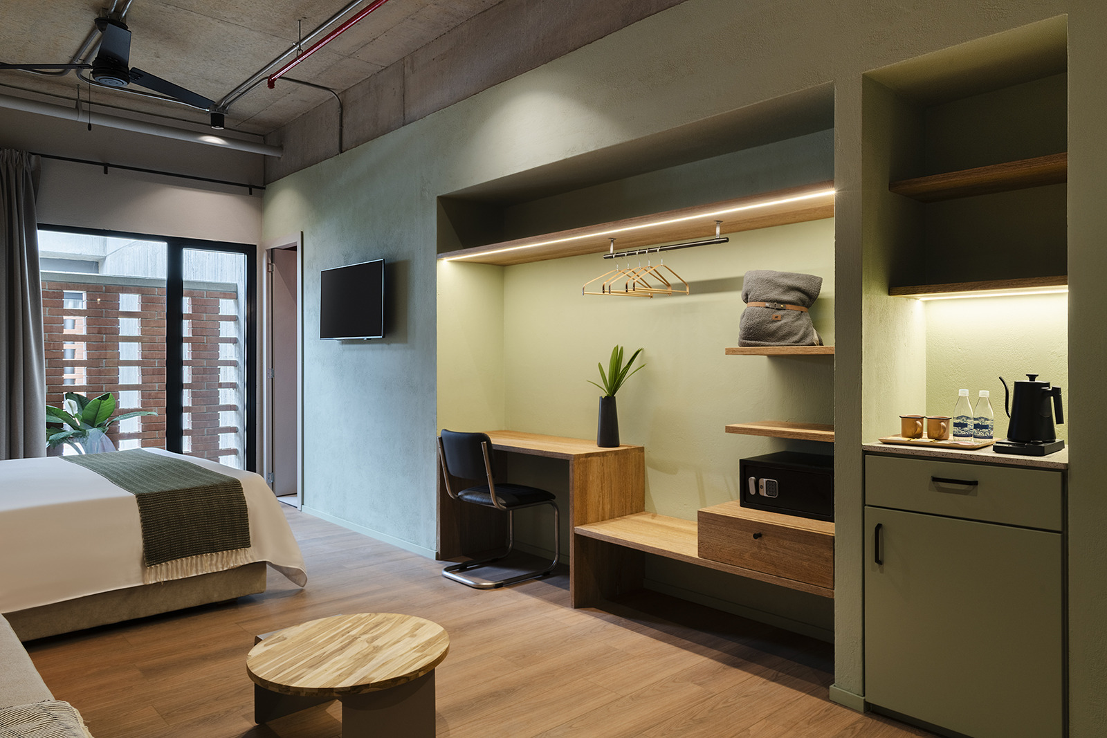 Modern hotel room with couch, chair, and art prints. Obra Hotels Medellin