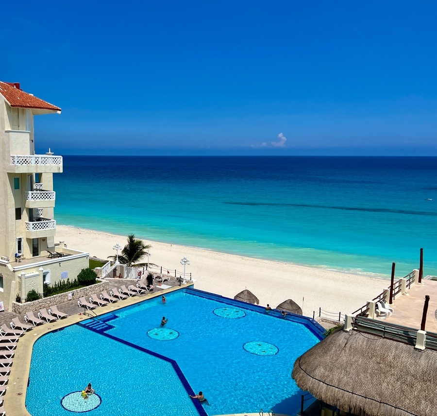 a large swimming pool in front of a white sandy beach