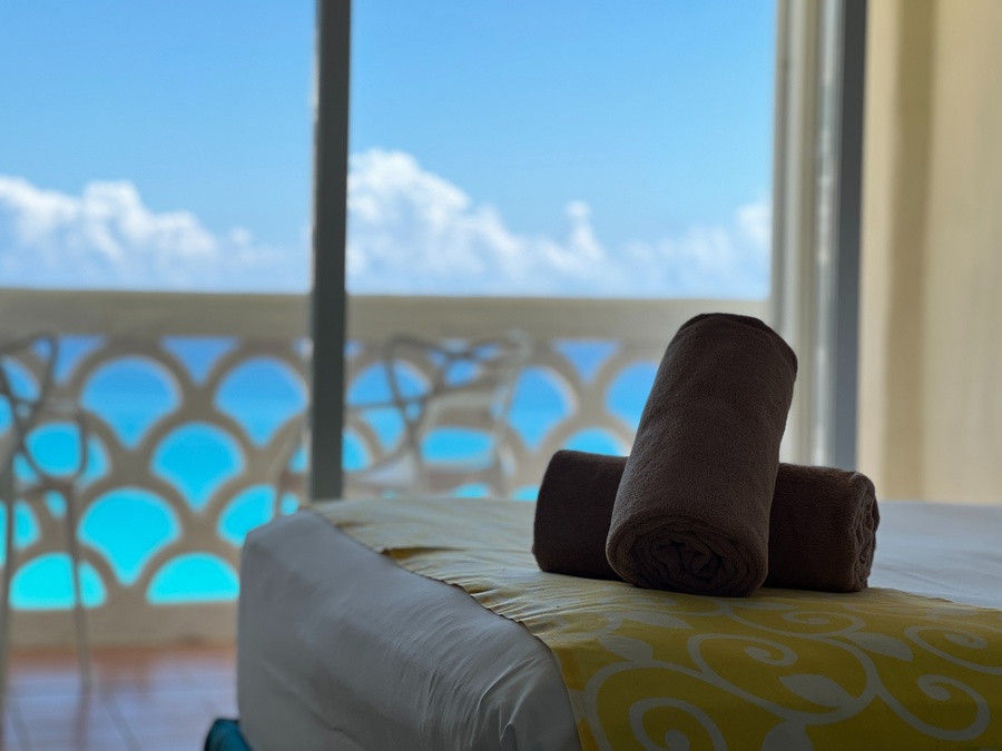 dos toallas están sobre una cama frente a una ventana con vista al océano
