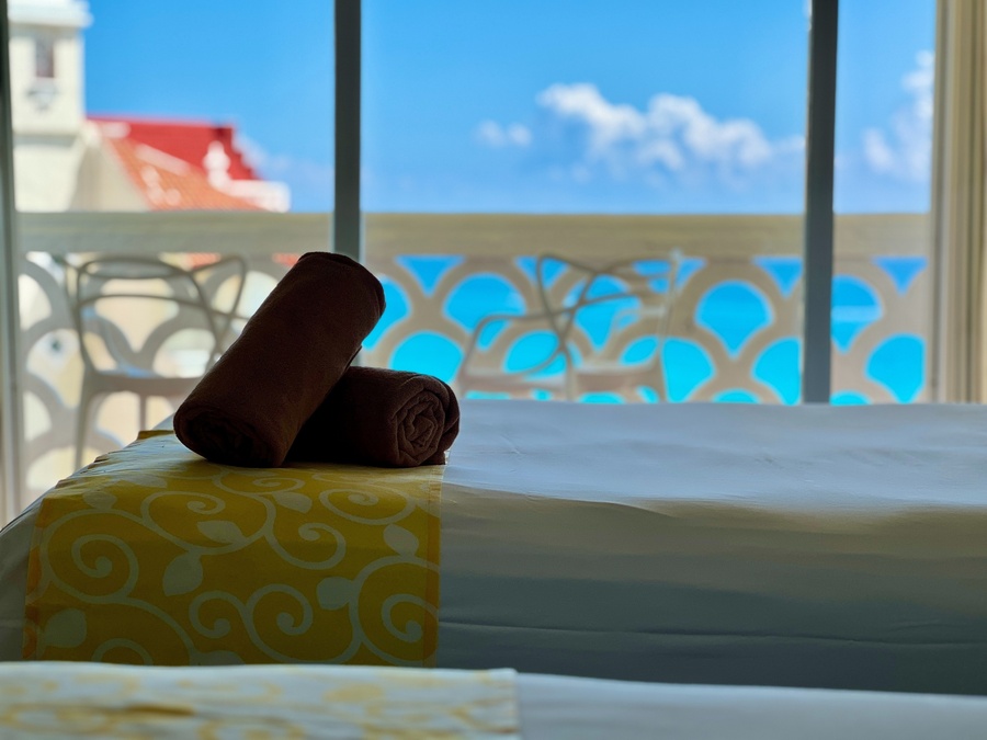 dos toallas están sobre una cama frente a una ventana con vista al océano
