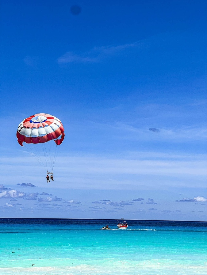 two people parasailing over the ocean with a boat in the background