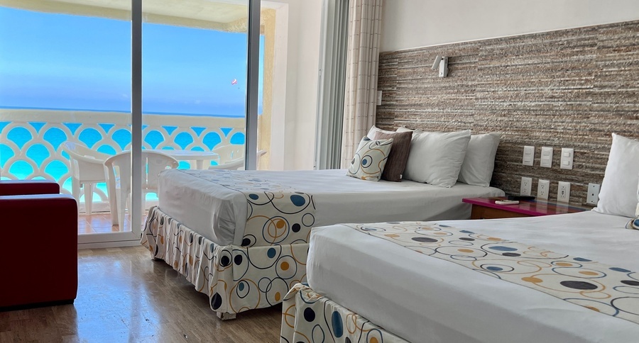 a hotel room with two beds and a balcony overlooking the ocean