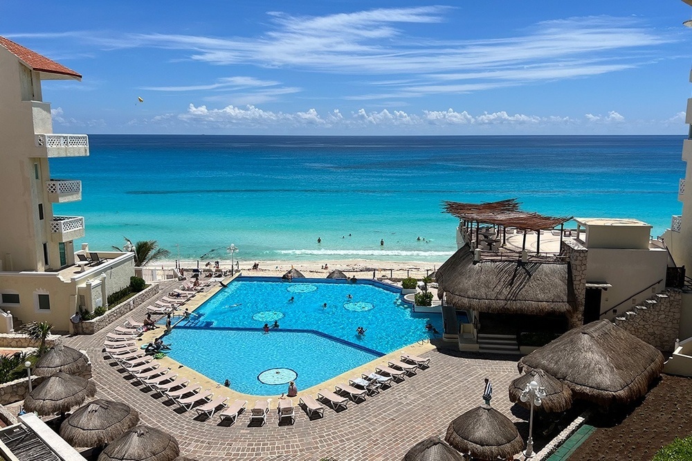a large swimming pool surrounded by chairs and umbrellas overlooking the ocean