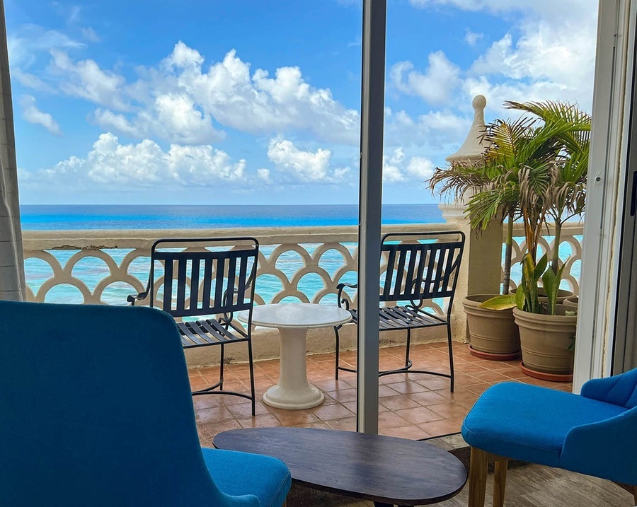 two chairs and a table on a balcony overlooking the ocean